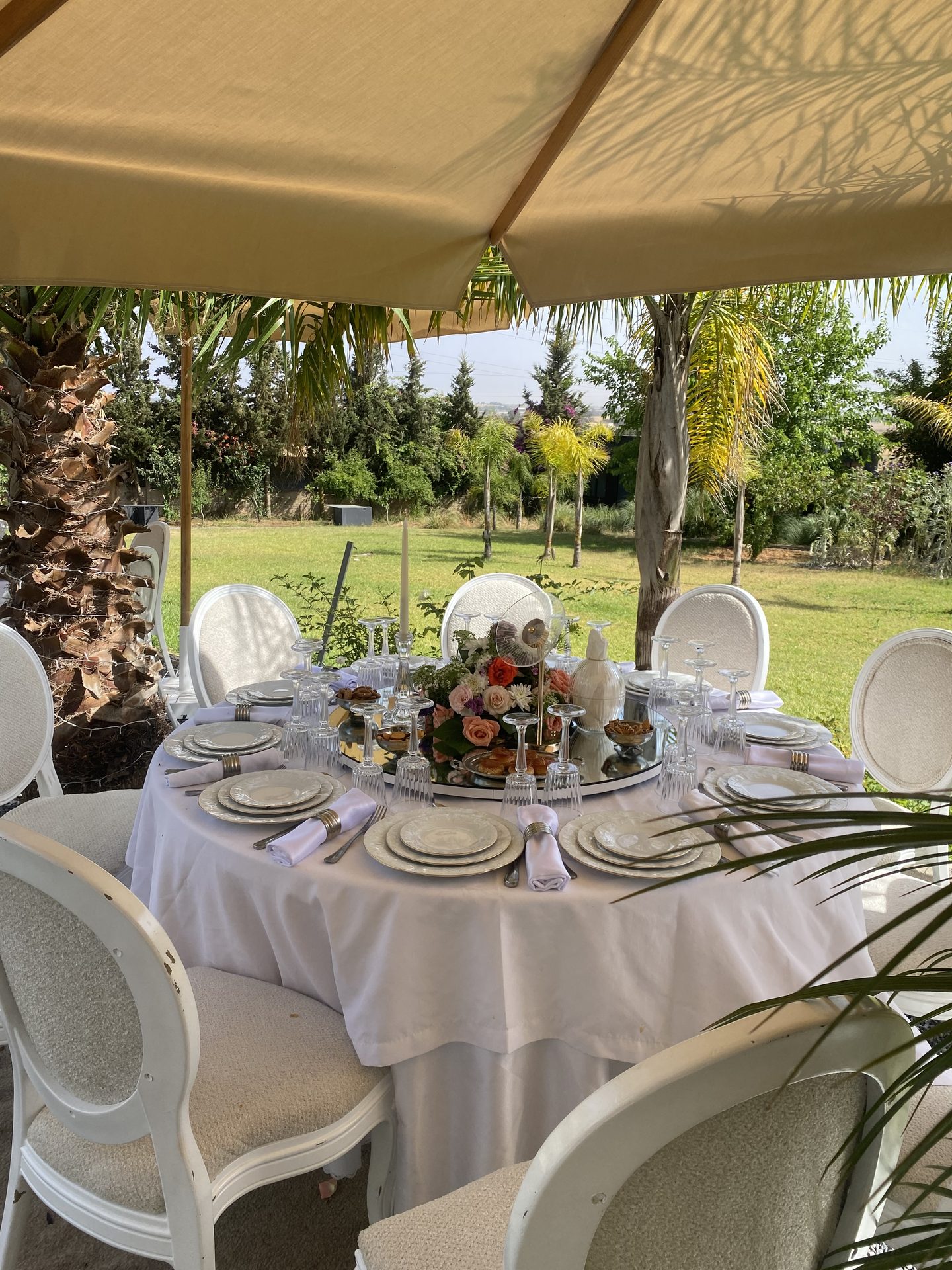 Table ronde dressée en extérieur sous tente, centre floral