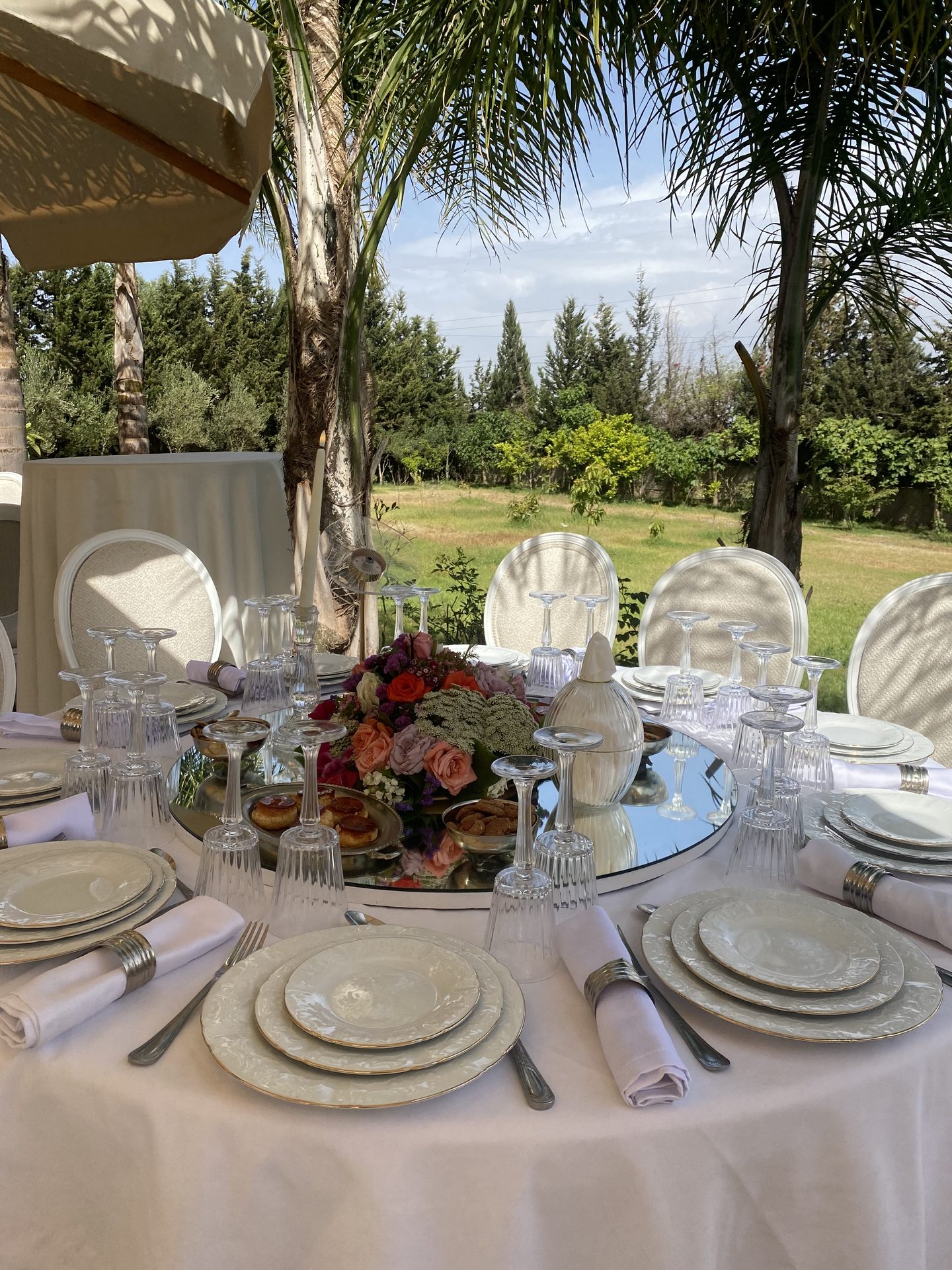 Table d'honneur en plein air entourée de palmiers, centre de roses