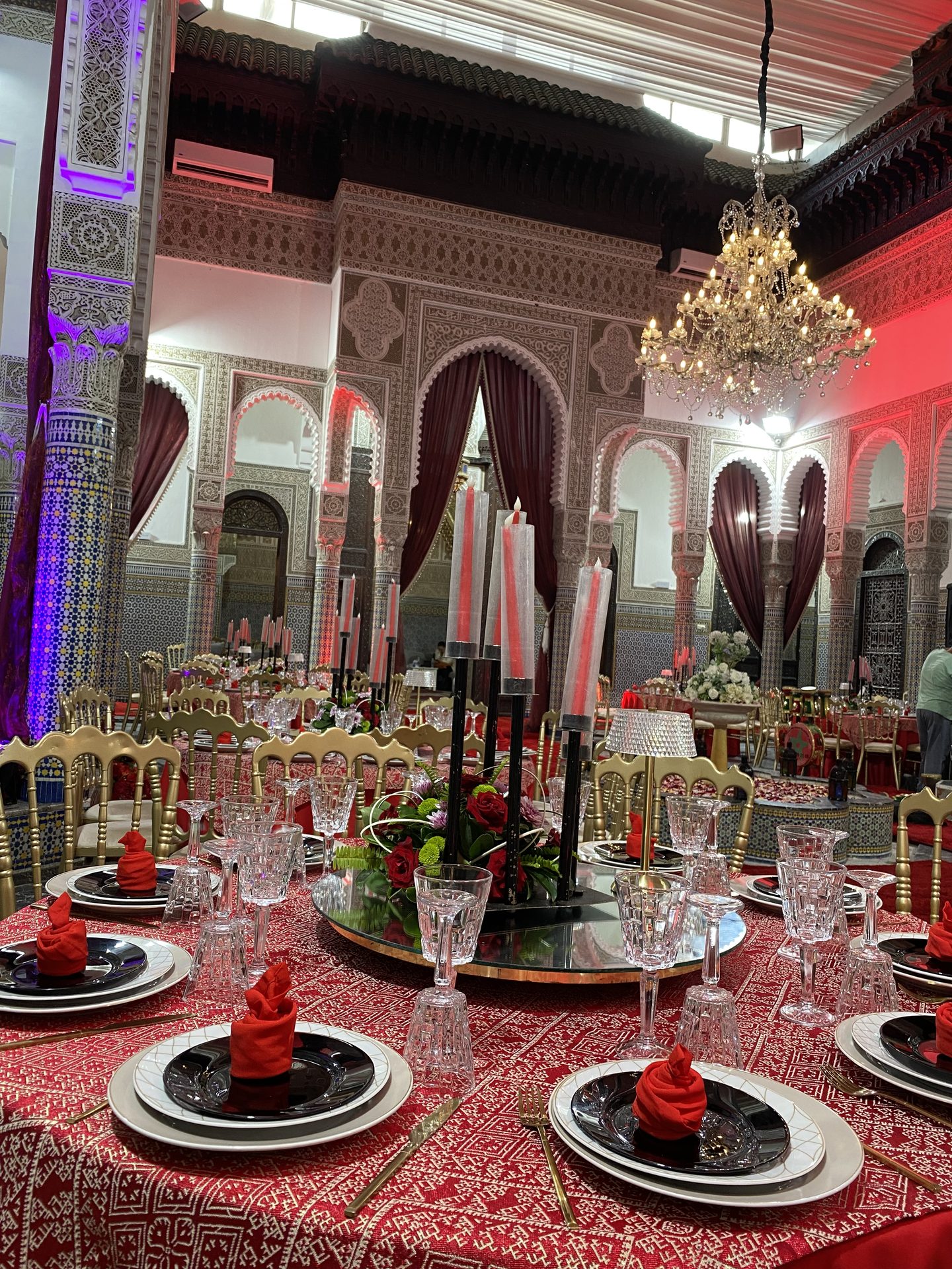 Salle de fête marocaine en rouge et or, roses rouges et candélabres