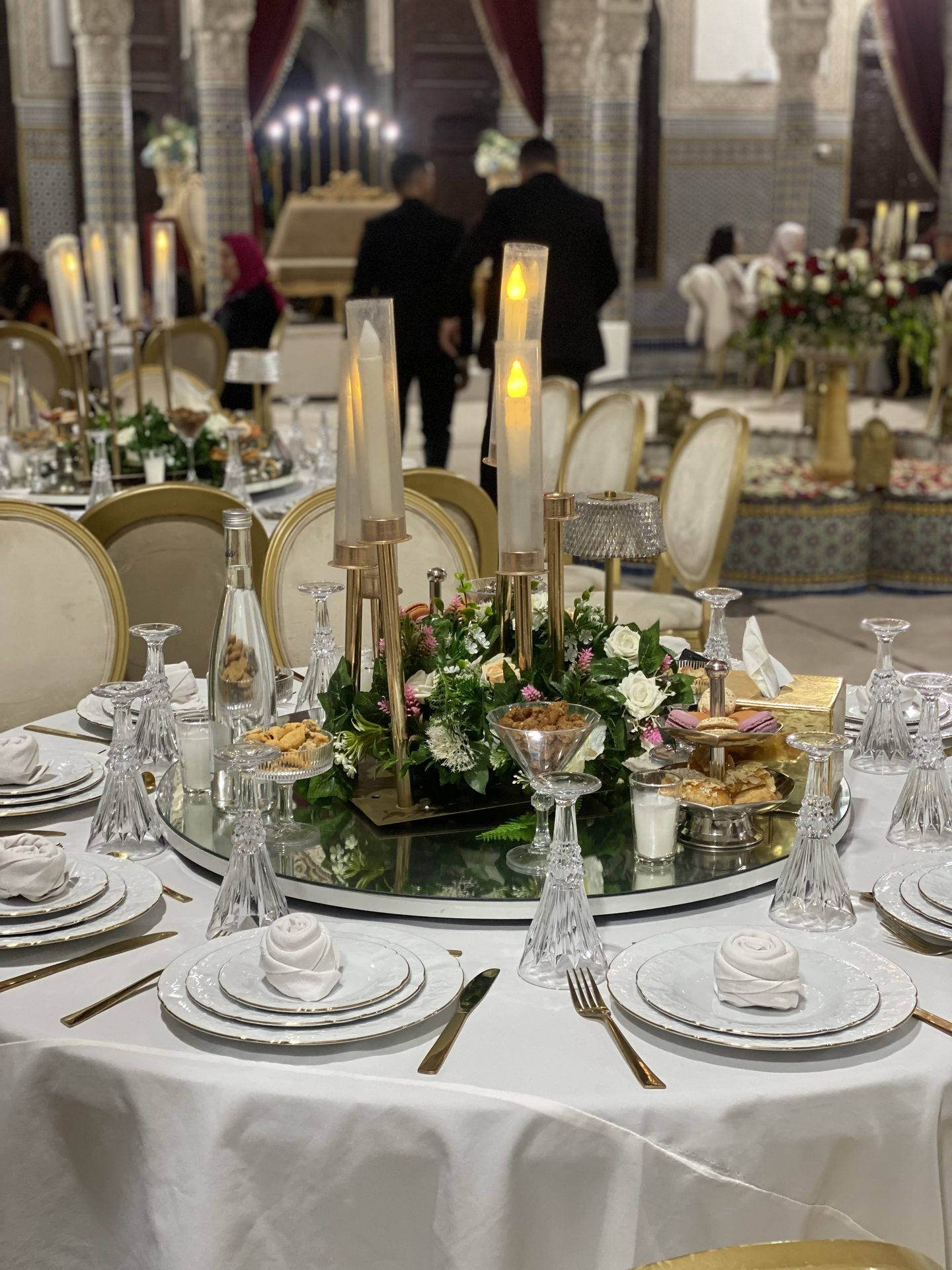 Centre de table au candélabre dans un riad, invités en arrière-plan