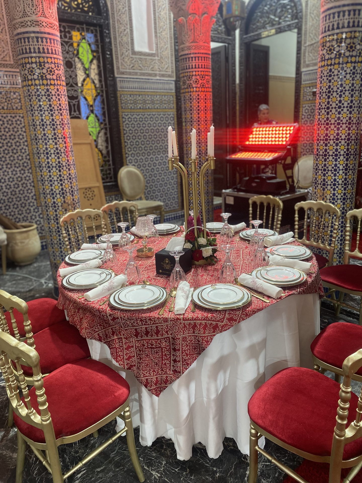Table marocaine rouge au candélabre, chaises dorées et velours rouge