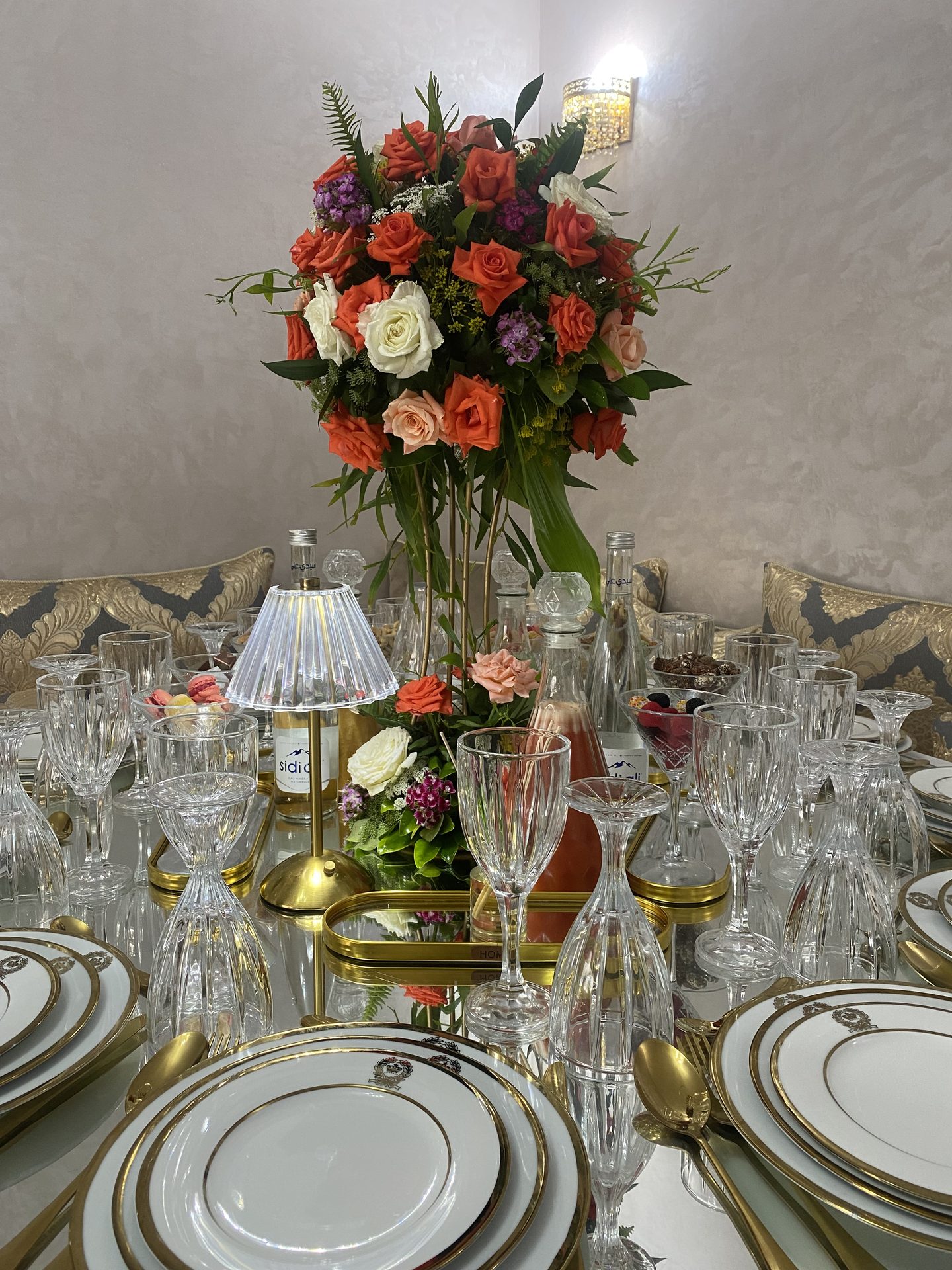 Table raffinée au haut centre de roses coraline et vaisselle dorée